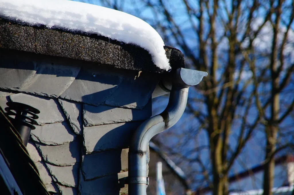 Snow-covered gutter and downspout during winter conditions